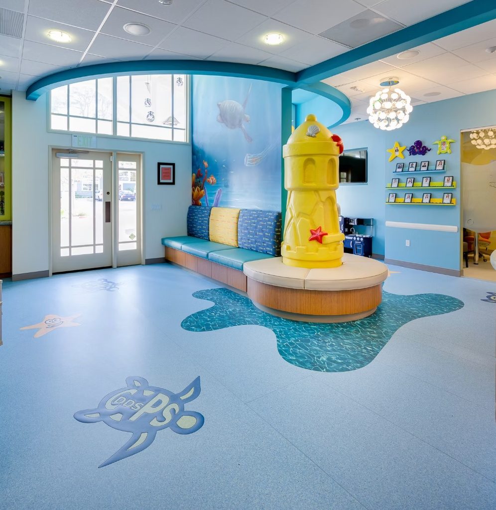 The entry of the CarlsbaDDS Pediatric Smiles office, its floor-to-ceiling ocean mural rising behind the bench