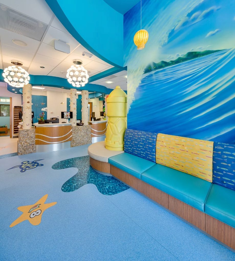 The waiting room at CarlsbaDDS Pediatric Smiles, with its painted wave mural and fish-print bench
