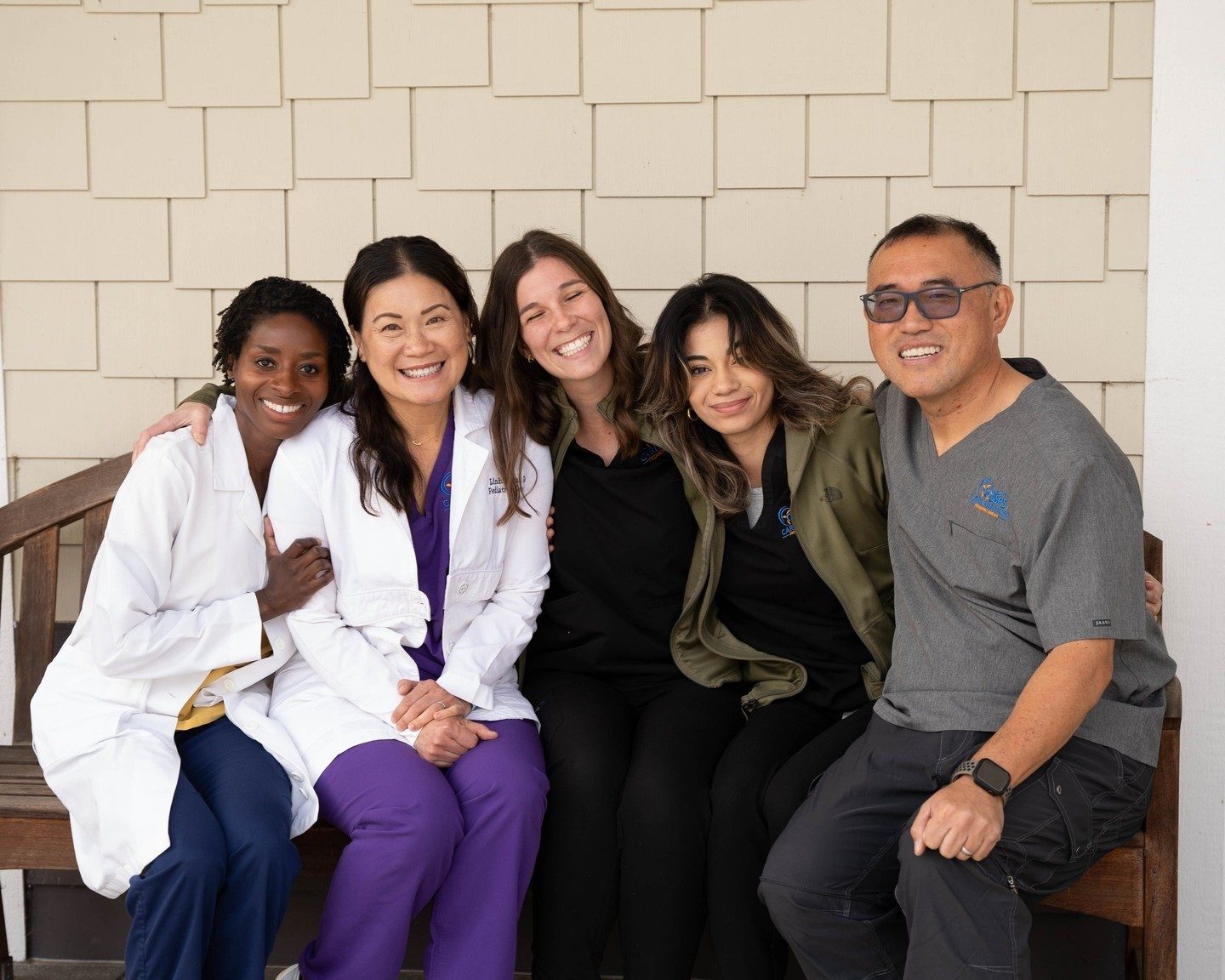 Doctors and team laughing together on the bench outside the office